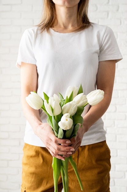 Junge Frau, die leeres weißes T-Shirt trägt, das Tulpenblumen hält.