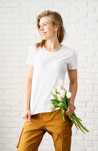 Junge Frau, die leeres weißes T-Shirt trägt, das Tulpenblumen hält.