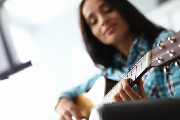 Junge Frau, die lernt, wie man Gitarre spielt