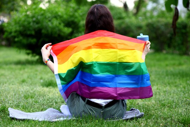 Foto junge frau, die lgbtq-flagge in der natur hält