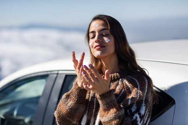 Junge Frau, die Lichtschutz auf ihrem Gesicht in der Schneelandschaft anwendet