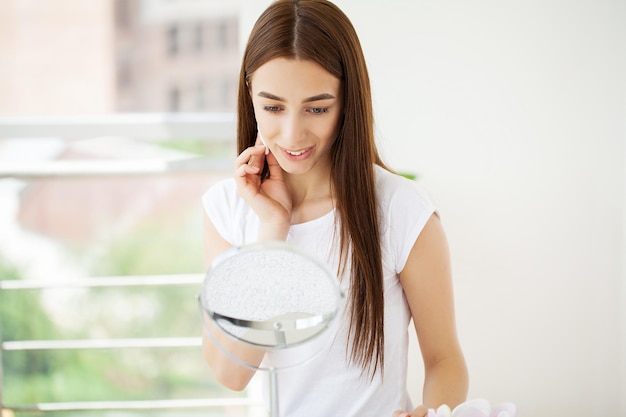 Junge Frau, die Make-up auf Gesicht zu Hause anwendet