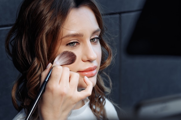 Junge Frau, die Make-up für das Hochzeitsfoto vorbereitet