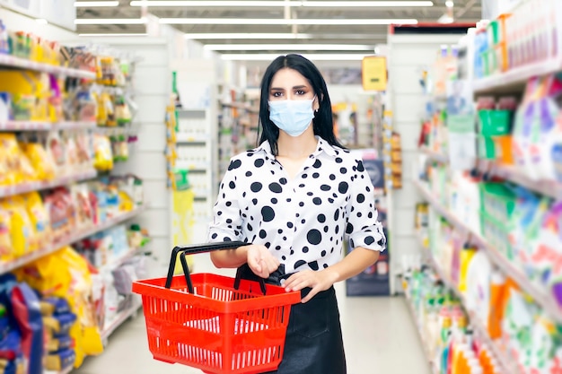 Junge Frau, die medizinische Einwegmaske beim Einkaufen im Supermarkt während des Ausbruchs der Coronavirus-Lungenentzündung trägt. Schutz und Verhinderung von Maßnahmen während der Epidemiezeit.