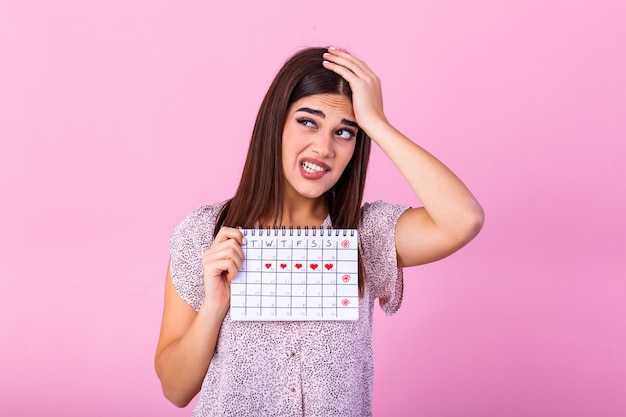 Junge Frau, die Menstruationskalender mit Überraschungsgesicht hält.