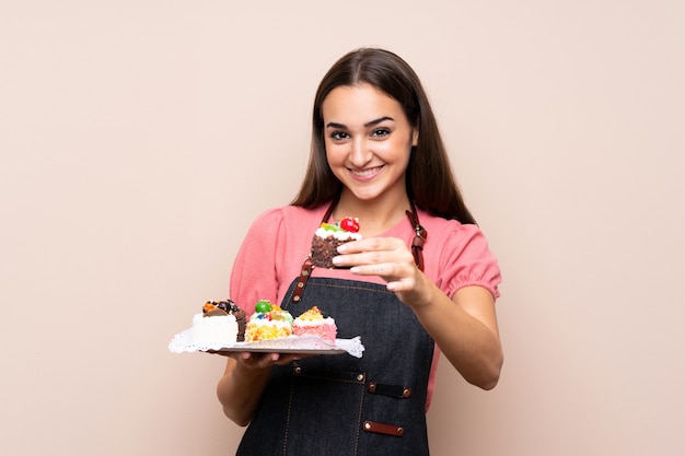 Junge Frau, die Minikuchen hält und sie anbietet