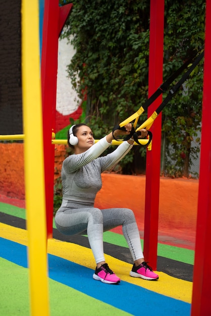 Junge Frau, die mit athletischen Trägern hockt