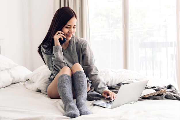 Junge Frau, die mit Computer auf Bett entspannt