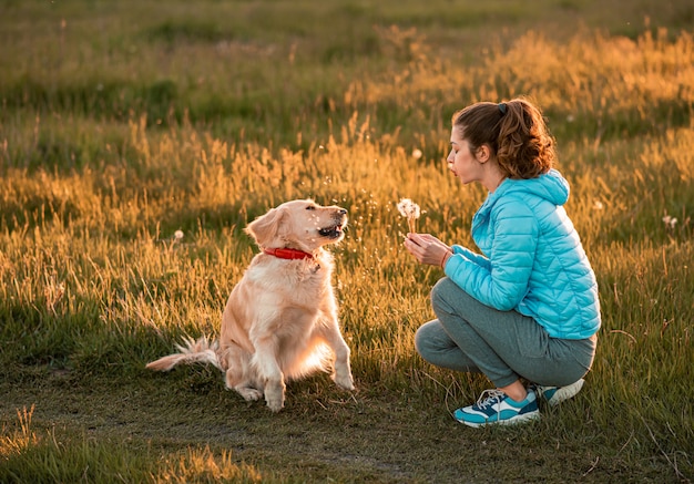 Junge Frau, die mit einem goldenen Retriever spielt