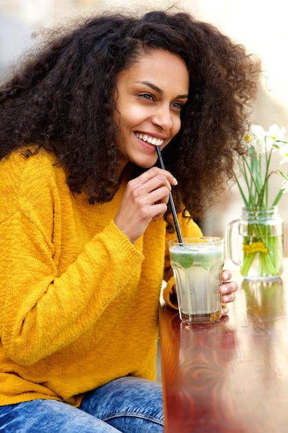 Junge Frau, die mit Getränk am Café lächelt