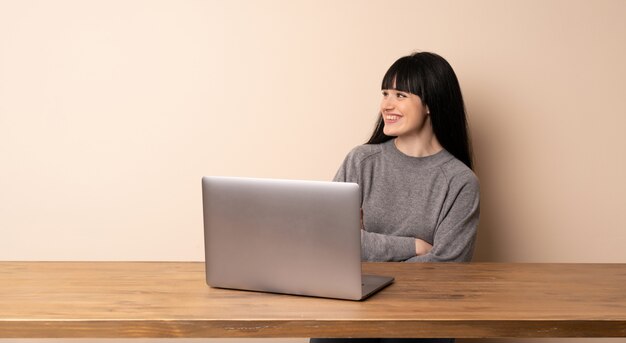 Junge Frau, die mit ihrem Laptop glücklich und lächelnd arbeitet