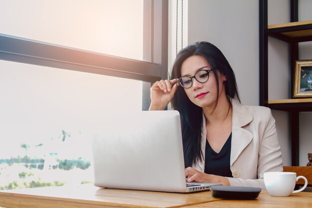 Junge Frau, die mit Laptop im Co-Arbeitsraum arbeitet