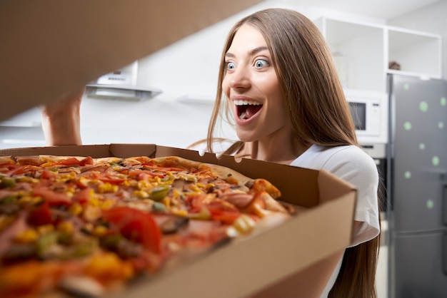 Junge Frau, die mit Vergnügen Pizza isst