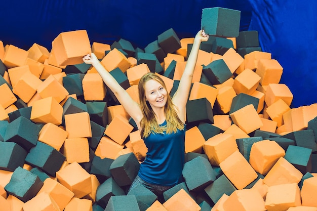 Junge Frau, die mit weichen Blöcken auf dem Indoor-Kinderspielplatz in der Schaumgummigrube im Trampolinzentrum spielt