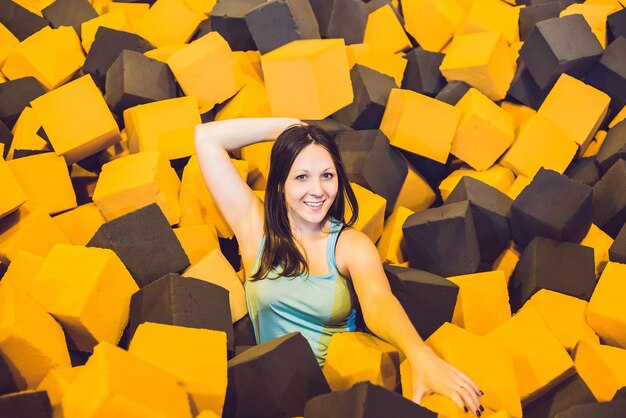 Junge Frau, die mit weichen Blöcken auf dem Indoor-Kinderspielplatz in der Schaumgummigrube im Trampolinzentrum spielt.