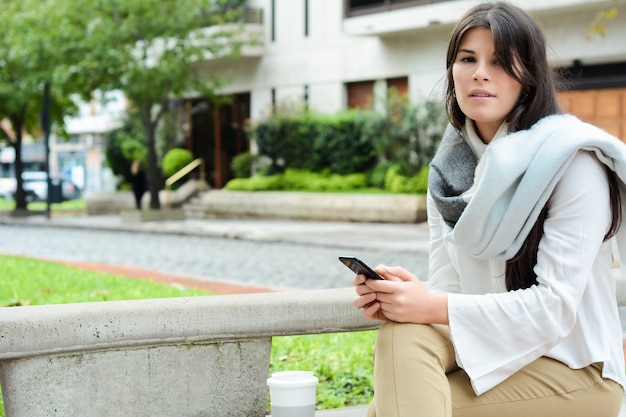 Junge Frau, die Mitteilung mit Smartphone sendet.