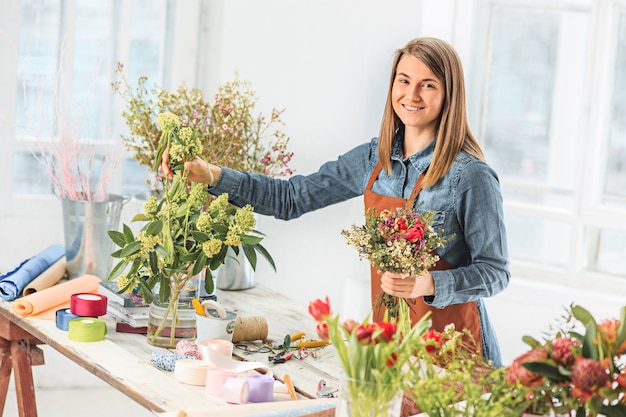 Junge Frau, die modernen Blumenstrauß der Mode der verschiedenen Blumen macht