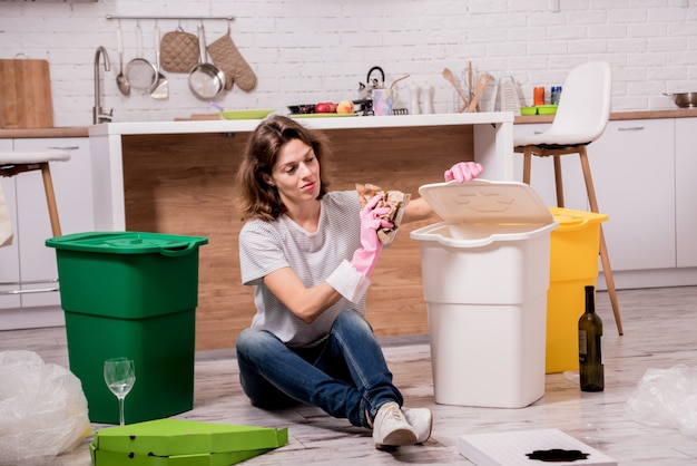 Junge Frau, die Müll an der Küche sortiert. Konzept des Recyclings. Kein Verlust