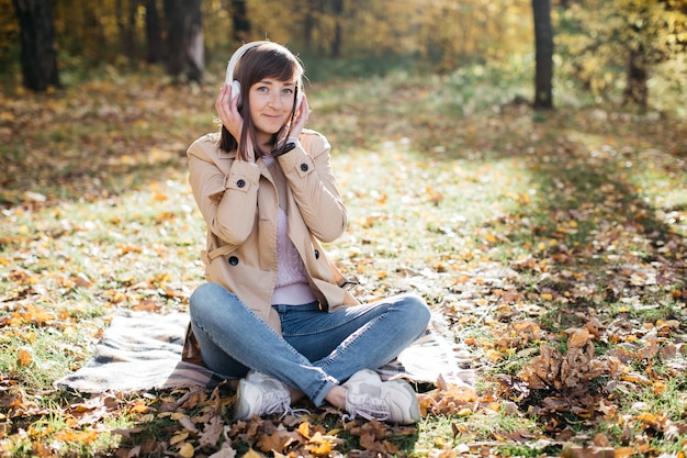 Junge Frau, die Musik mit Kopfhörern im Herbstwald hört