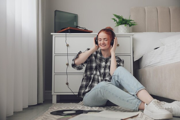 Junge Frau, die Musik mit Plattenspieler im Schlafzimmer hört