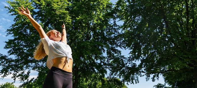 Junge Frau, die nach dem Sport die Frühlingsbrise im Park genießt