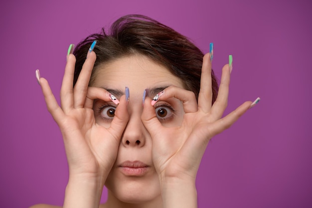 Junge Frau, die ok Geste wie ein Fernglas mit den Händen macht