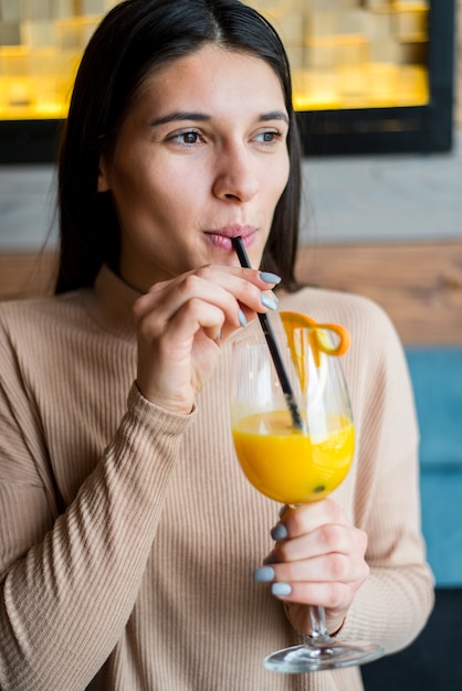 Junge Frau, die Orangensaft im Café trinkt