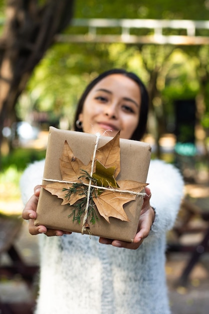 Junge Frau, die organisches verpacktes Weihnachtsgeschenk hält