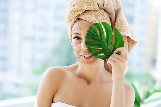 Junge Frau, die Peeling auf Gesicht im Badezimmer anwendet.