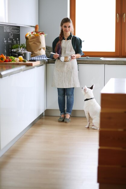 Junge Frau, die Pfannkuchen in der Küche kocht, die in der Nähe des Ofens steht