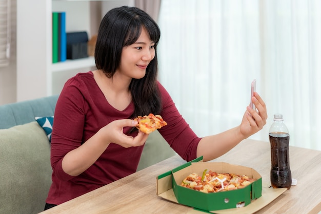 Junge Frau, die Pizza in einem Videoanruf isst