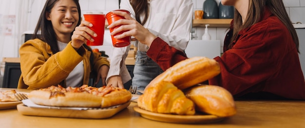 Junge Frau, die Pizza isst und lacht, während sie mit ihren Freunden in einem Restaurant sitzt Gruppe von Freunden, die sich beim Essen und Trinken im Café amüsieren