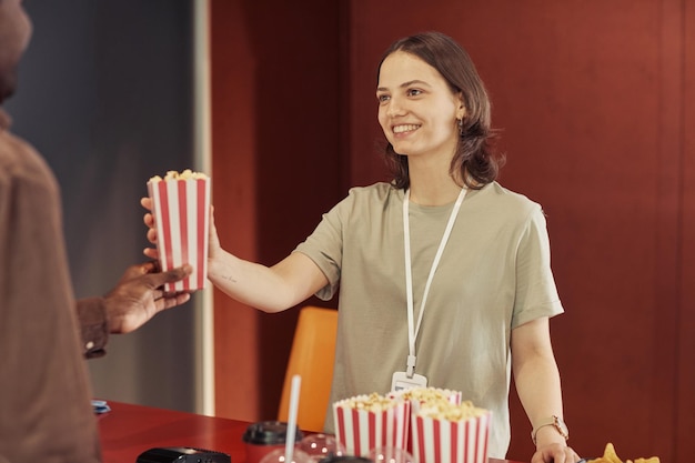 Junge Frau, die Popcorn an Leute verkauft