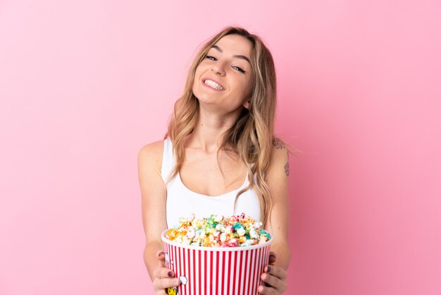 Junge Frau, die Popcorn über lokalisierter Wand hält