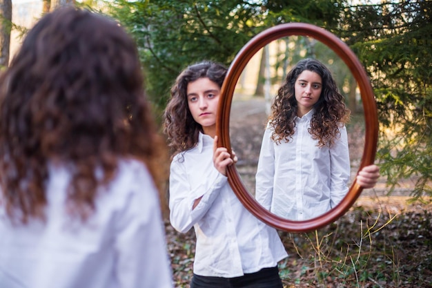 Junge Frau, die Reflexion der Zwillingsschwester im Wald zeigt