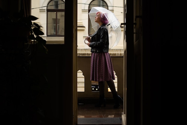 Junge Frau, die Regenschirm hält Herbststadthintergrund