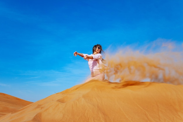 Junge Frau, die Sand in der Orande-Wüste wirft