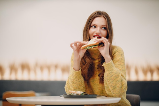 Junge Frau, die Sandwich im Innencafé isst