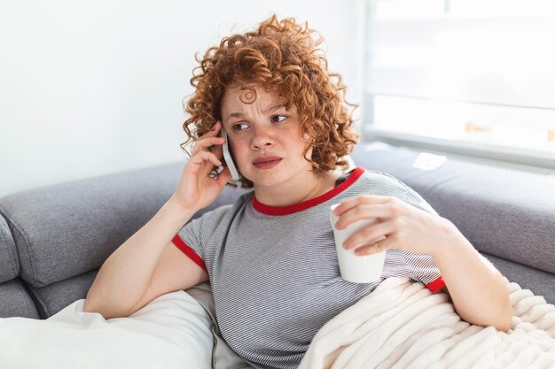 Junge Frau, die schlechte Nachrichten per Telefon erhält. unglückliche Frau, die auf dem Handy spricht und nach unten schaut.