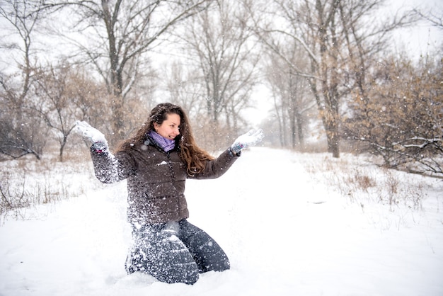 Junge Frau, die Schnee wirft, glücklich und Spaß