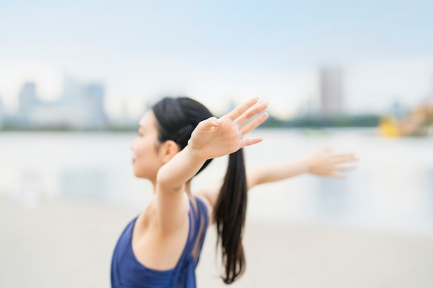 Junge Frau, die sich am Strand der Stadt ausdehnt und tief einatmet