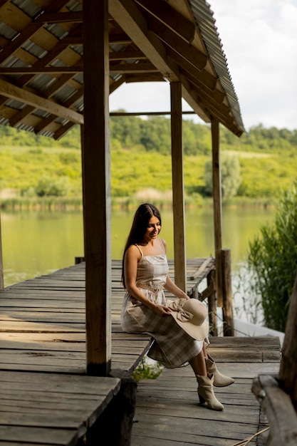 Junge Frau, die sich auf dem Holzsteg am ruhigen See entspannt