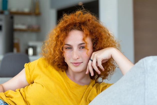 Junge Frau, die sich auf ihrer Couch entspannt Porträt einer schönen Frau, die zu Hause lächelt Frau in lässigem Blick in die Kamera mit Kopierraum