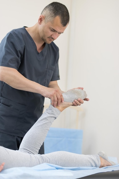 Junge Frau, die sich im Innenbereich einer Osteopathiebehandlung unterzieht und den Fuß massiert
