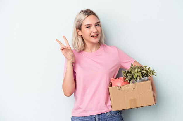 Junge Frau, die sich über isolierten Hintergrund bewegt, fröhlich und sorglos und zeigt ein Friedenssymbol mit den Fingern.