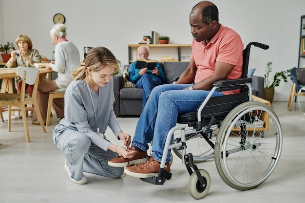 Junge Frau, die sich während ihrer Arbeit im Pflegeheim um einen Mann mit Behinderung kümmert