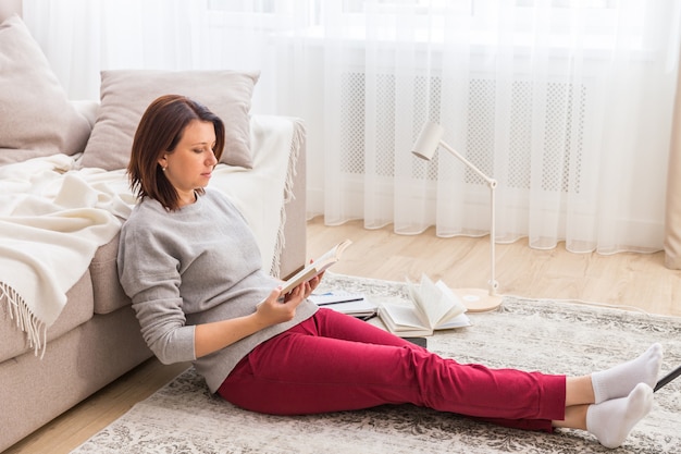 Junge Frau, die sich zu Hause auf Bodenlesebuch entspannt