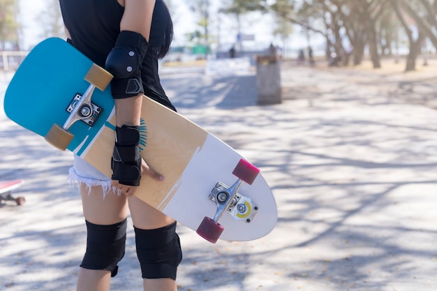Junge Frau, die Skateboard der alten Schule hält, die Schutzausrüstung trägt
