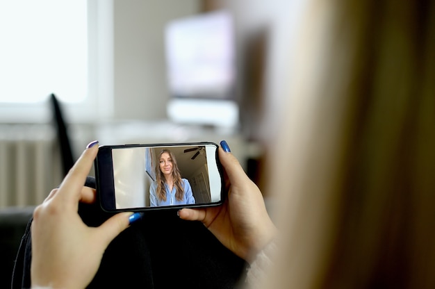 Junge Frau, die Smartphone für Videoanruf verwendet. Hochwertiges Foto