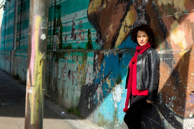 Junge Frau, die Sonne auf der Straße mit Graffitiwand genießt.